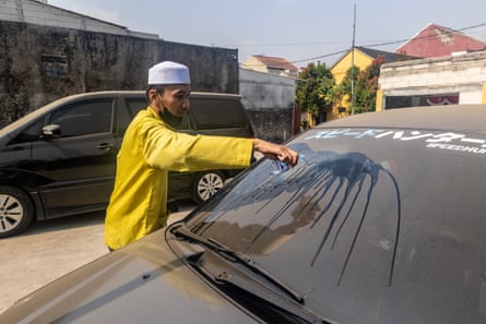 A man clears volcanic ash from his car windscreen