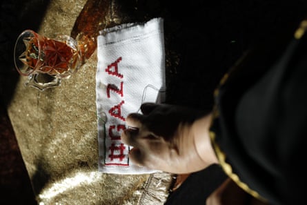 A pair of hands embroidering #GAZA on a piece of fabric.