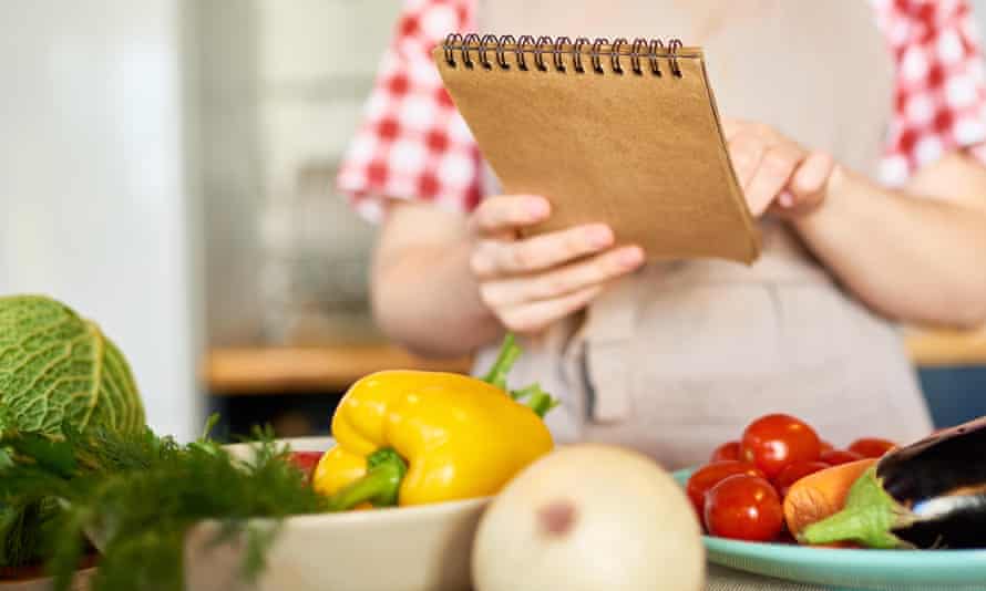 Holding a note pad over some vegetables