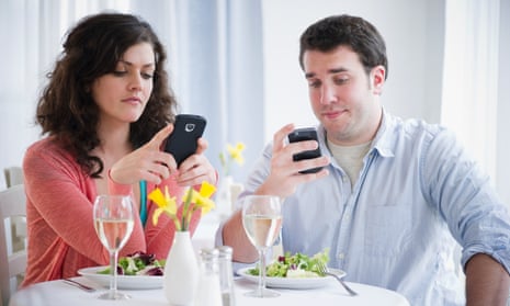 Two diners looking at their phones
