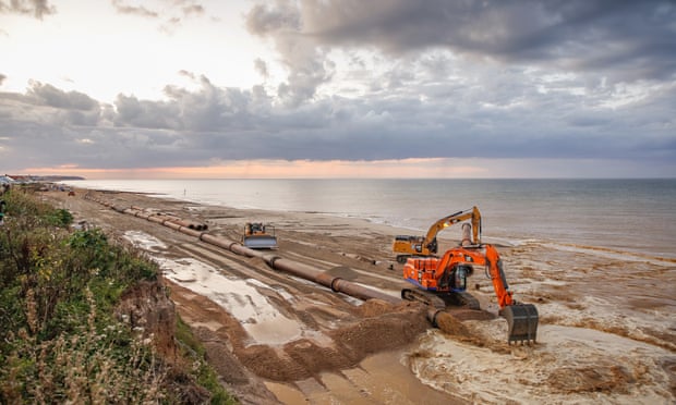 A digger on the Norfolk coast moving sand.