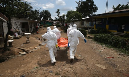 An Ebola burial team carries the body of a woman through a suburb of Monrovia, Liberia.