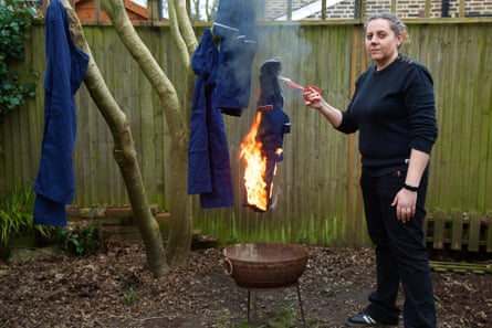 A nurse burns her uniform on a fire pit in a garden