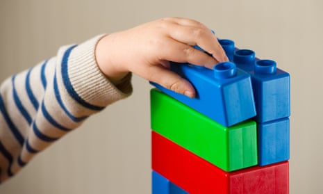 A preschool-age child playing with plastic building blocks