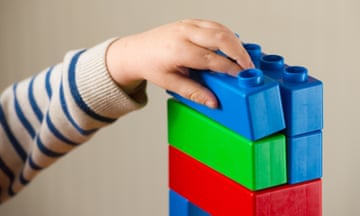 Young child playing with building blocks with a striped jumper