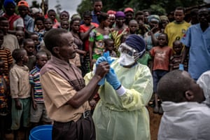 A Red Cross burial worker shows a man how to put on protective gloves before the inspection of the body of an 11-month old girl who died during the Ebola outbreak in the town of Rutshuru in North Kivu province, February 2020. Finbarr O’Reilly