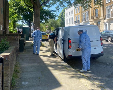 A trio of police staff, two in crime scene protective gear, on a street in London
