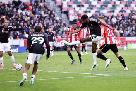 Alexander Isak strikes the ball mid-air to score, as a Brentford defender challenges
