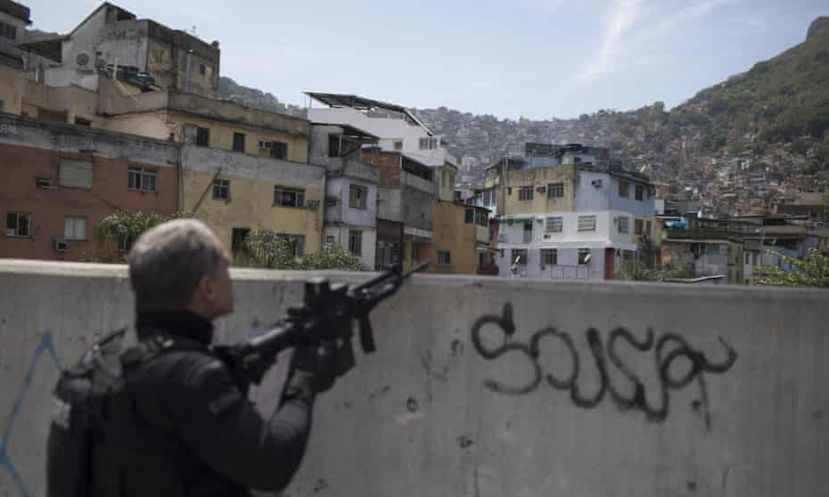 A police officer takes a position during an operation in the Rocinha favela in Rio de Janeiro, Brazil Friday.