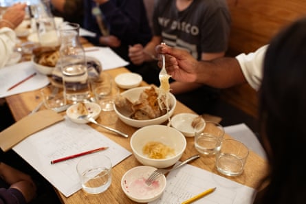 Close up of hands holding a fork, dangling some sauerkraut over a bowl.