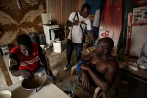 Asuma Yaw at dinner time in his shack as he receives a visit from Atta Jacob, a CGIL union organiser (pictured rear).