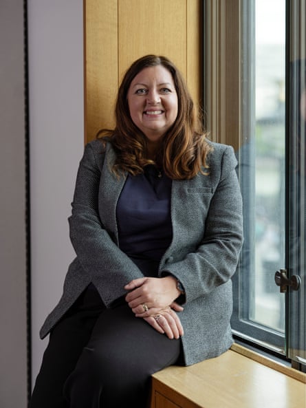 Kirsty McNeill smiles while sitting on a windowsill in an office