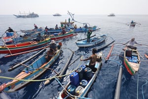 Filipino fishers dock their boats beside a government supply ship distributing oil and food, 20 September 2023
