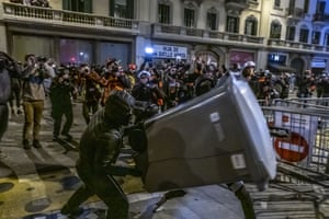 A protester throws a rubbish bin at police in Barcelona. Shops in the city centre were targeted and windows broken