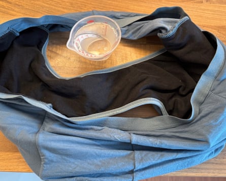A pair of grey and black period pants next to a small jug of water