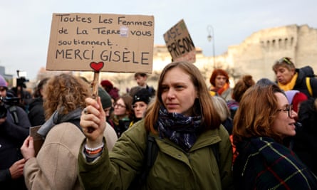 A woman holds a placard reading in French “all women on earth support you, thank you Gisele”
