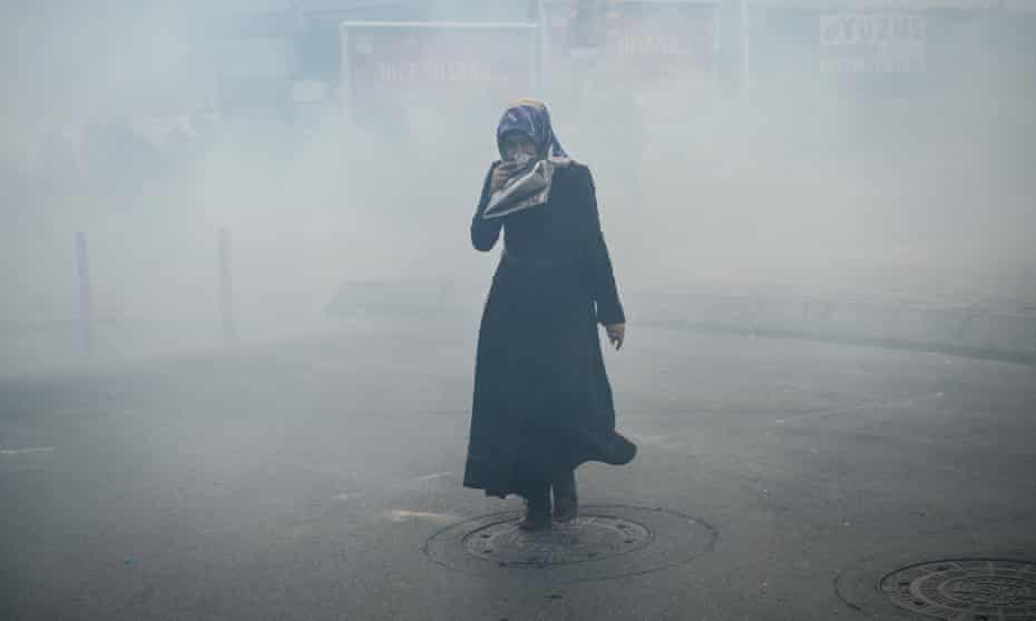 A woman covers her face against tear gas