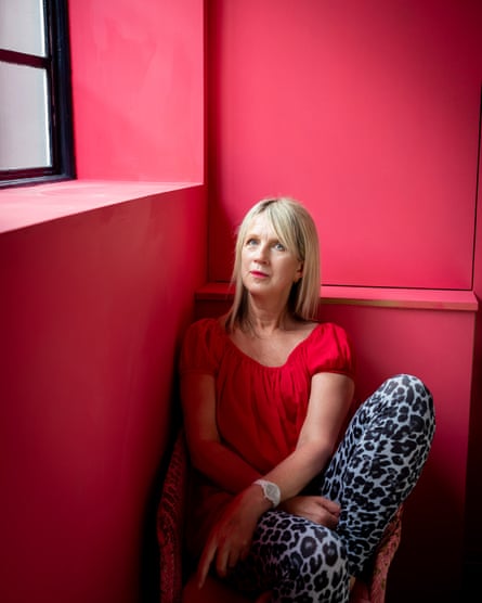 Julie Myerson at home in London, sitting in a corner with bright pink walls.