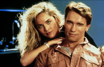The actors pose in character, her leaning on his shoulder from behind