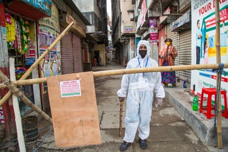 A man in a white protective suit guards a closed-off alleyway