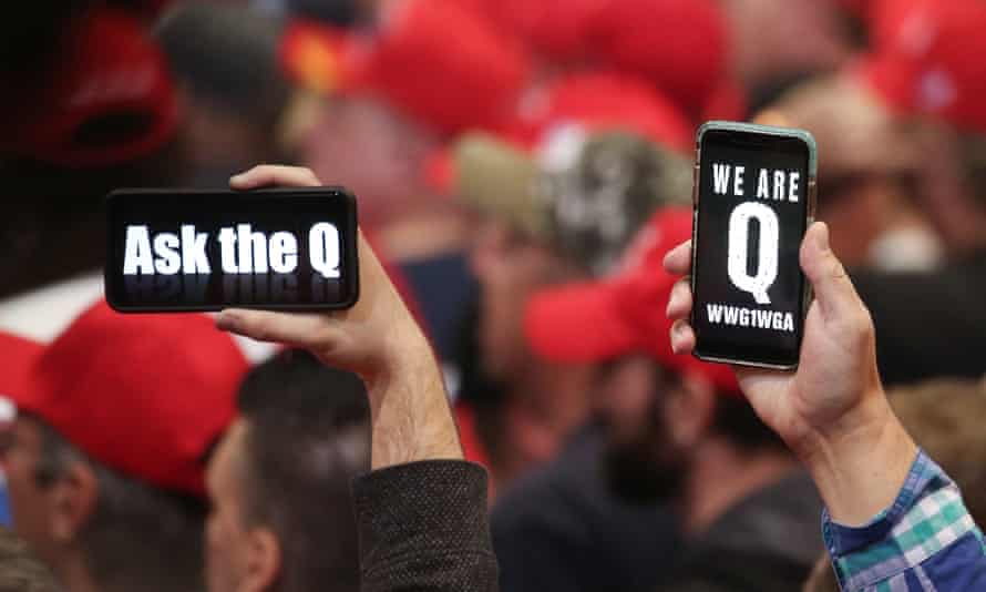 Trump supporters hold up their phones with messages referring to the QAnon conspiracy.