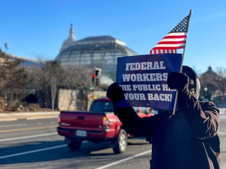 A supporter of federal workers holds a sign near the US Capitol in support of federal workers on Thursday.