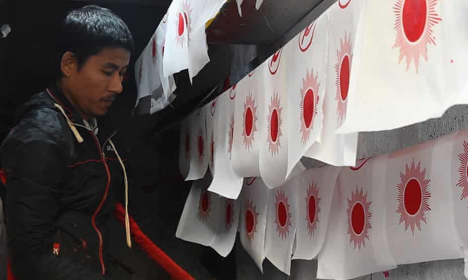 A worker makes political party flags
