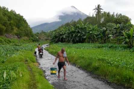 Villagers walk from their villages near Mount Mayon