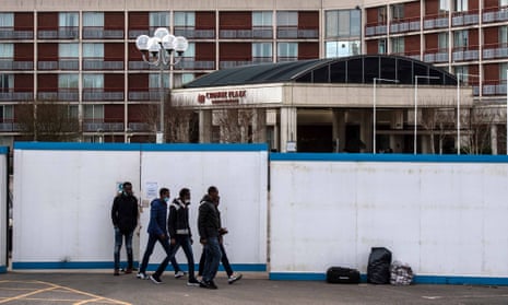 Asylum seekers exit the Crowne Plaza hotel through an exterior perimeter wall that has been installed while they stay at the hotel on 24 February 2021.