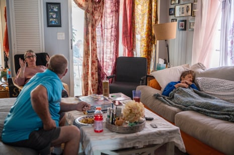 three people in a living room, one sleeping on a couch.