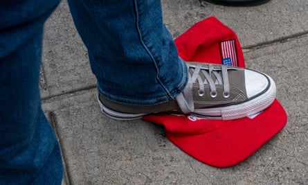 Gray Chuck Taylor sneaker on bright red hat on pavement.