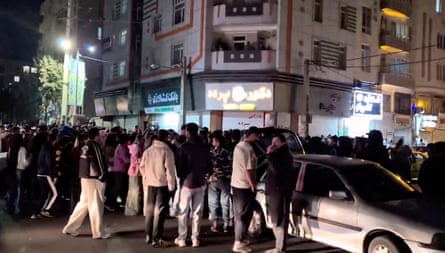 Video screengrab showing crowd of people standing on a street corner at night
