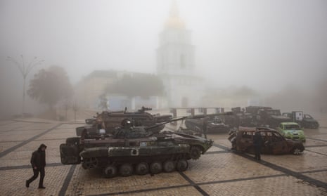 A man walks past destroyed Russian military vehicles outside a golden-domed monastery.