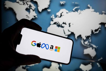 A silhouette hand holding a phone showing the google, apple, meta, amazon and microsoft logos on it