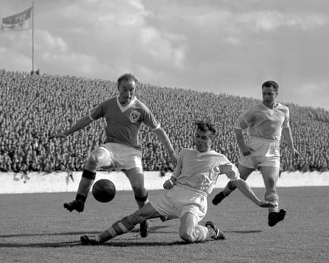 Stanley Matthews in action as a player slides to tackle him before a packed crowd