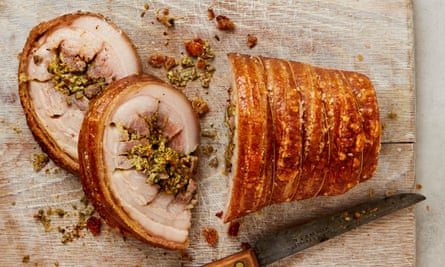 A porchetta with two slices cut off on a chopping board
