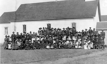 A photo dated c 1910 of the Marieval mission church and its congregation as it stood next to the Marieval Indian residential school, Canada.