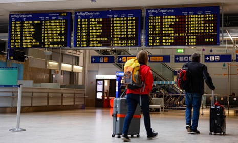 Travellers look at the departure board at Nuremberg airport on Monday