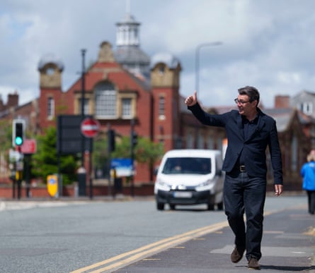 Andy Burnham gives a thumbs up while walking along a road.