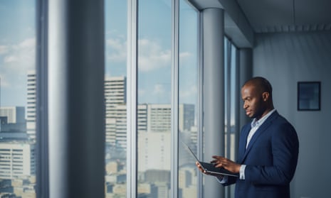 Thoughtful Black Businessman in a Tailored Suit Using Laptop while Standing in Office Near Window on Big City. 
