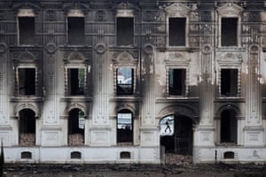 A grand, three-storey building with rubble spilling out of the windows. The exterior is stained by the fire and smoke