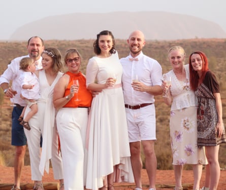 The bride and groom in front of the rock surrounded by well wishers