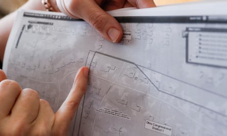 A woman’s hands hold up a map, pointing to a property with a line drawn through it.