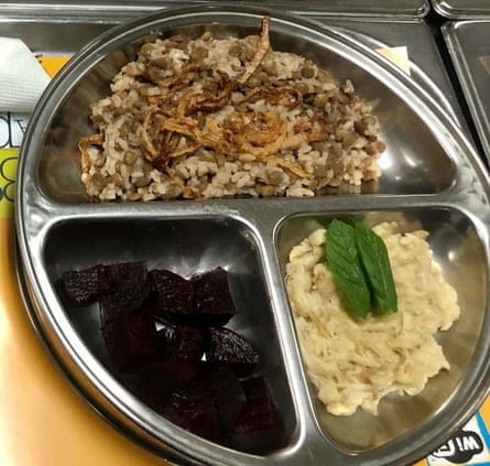 A metal tray divided into three parts, with rice in the top section and sliced beetroot in one, and hummus topped with a garnish in another.