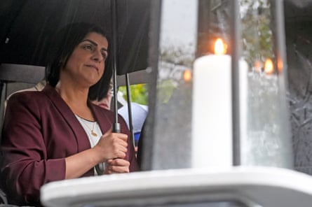 Woman holds umbrella; candle in the foreground.