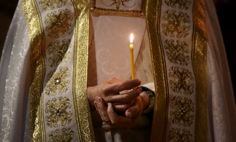 A Catholic priest holds a candle during a Good Friday service.