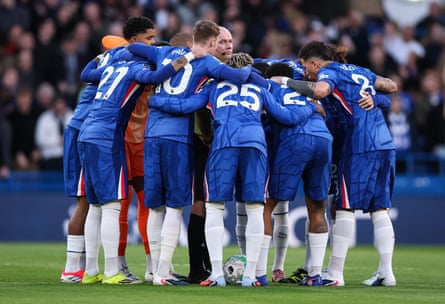 Chelsea players in a huddle surrounding the referee, Paul Tierney