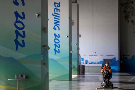A woman wearing a face mask cleans the floor at the main Media Centre in Beijing before the Games.