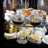 A man in coveralls and baseball hat hands Morwenna several packs of butter in front of a fridge stacked with more butter