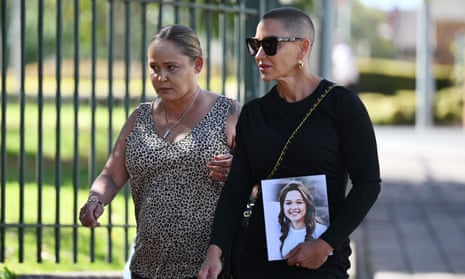 Two women arrive at court, one holding a photograph of a teenage girl